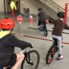 children ride bikes around a course at the fire station